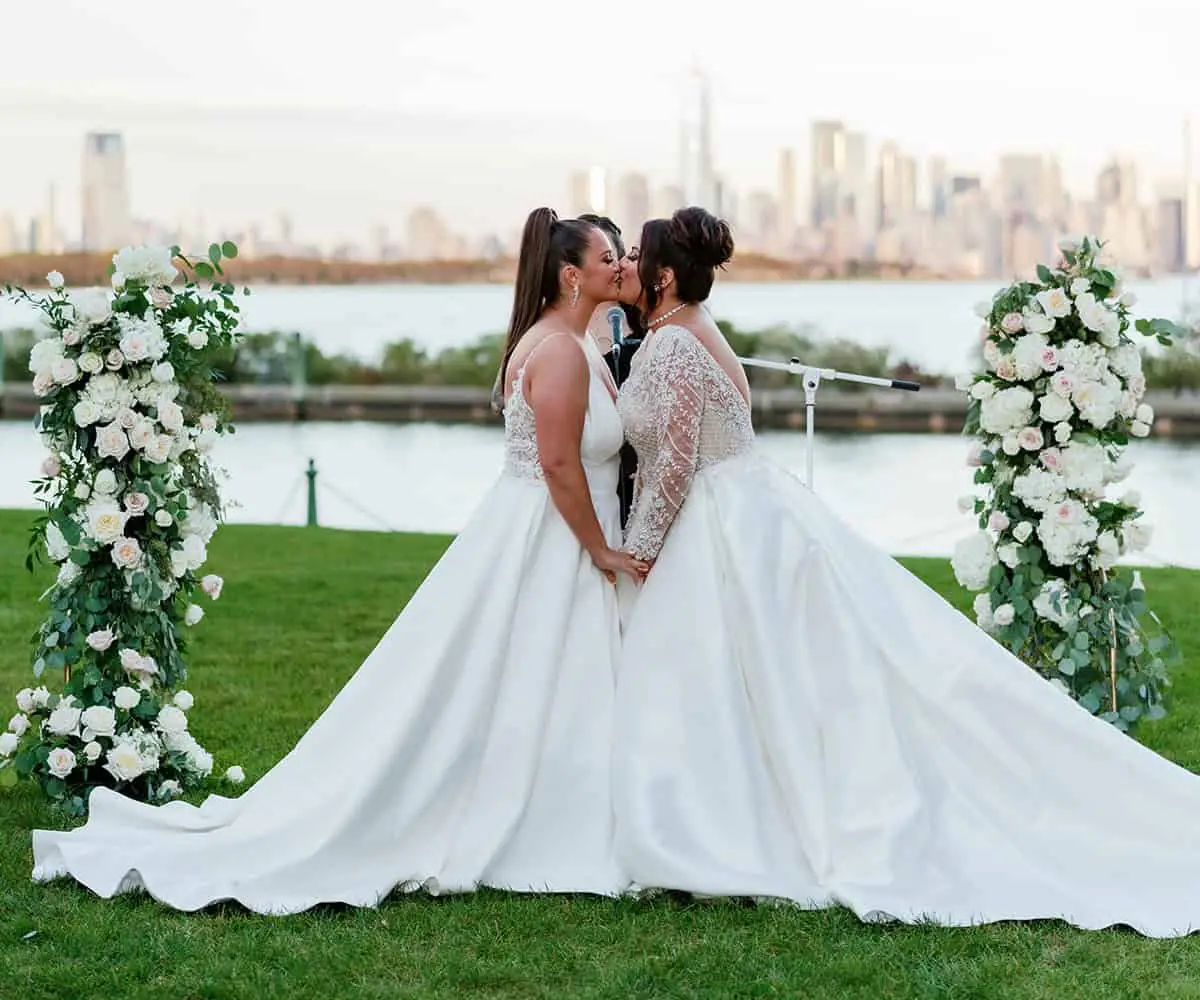 Two brides kissing at alter outdoors at Hudson House