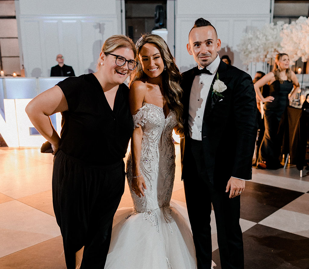 Wedding couple smiling with event stylist at wedding