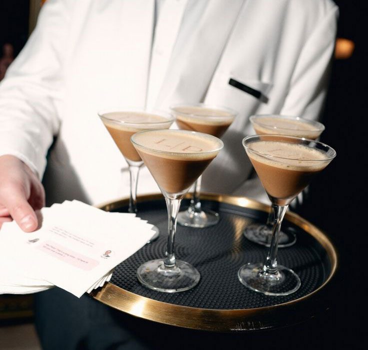 Waiter passing tray of espresso martinis